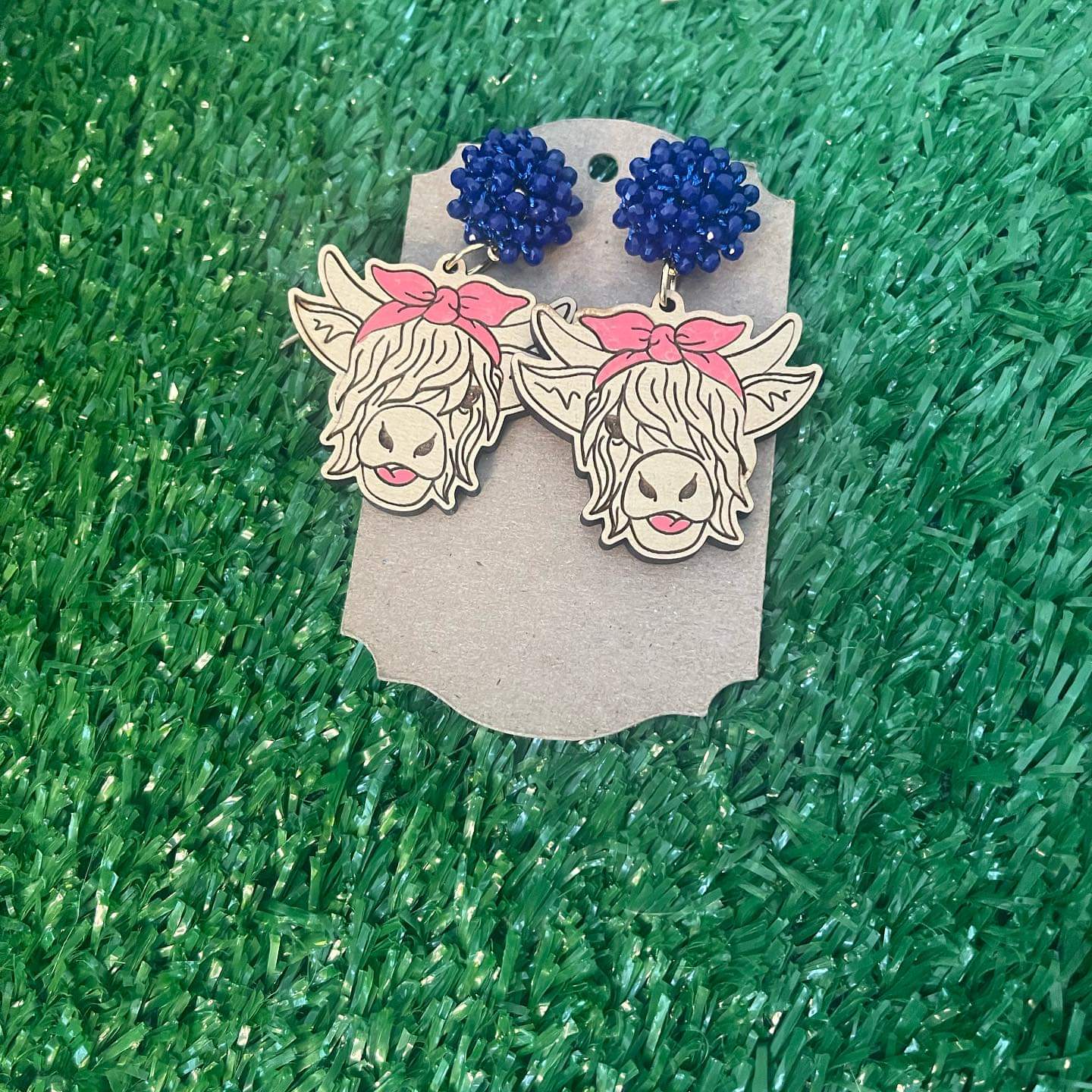 Laser engraved cow earrings with blue pom stud